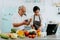 Senior Asian couple using a laptop while cooking in kitchen at home. 70s Elderly man and woman in relationship