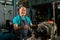 A senior Asian craftsman, standing closely and carefully controlling a lathe, inside a small factory of his family business