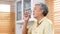 Senior asian man drinking water while standing by window in kitchen background, elderly retirement people and healthy lifestyles