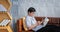 Senior Asian man reading book and using smart phone on sofa in living room at home  Portrait of Asian elderly man is Relaxing and