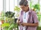 A senior Asian man working in a planting hobby room with happiness. Idea for green lover who plants tree and botany in corner of