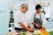 Senior Asian married couple cooking food at kitchen home. Elderly 70s man and woman preparing ingredients at kitchen