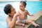 Senior asian woman is enjoying time with her adorable one year old grandchild in a swimming pool