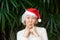 Senior asian woman in font of palm tree wearing Santaâ€™s hat. Christmas, New Year, tropical holiday concept. Text space