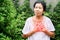 Senior Asian woman suffering from heartburn, chest pain, difficult to breathe standing outdoor