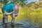 Senior, athletic man is splashing and rinsing his face in a lake