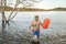 senior athletic, overweight man is finishing open water swimming with a swim buoy in a mountain lake