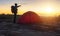 Senior backpacker standing beside tent on the hill in during sunrise is holiday