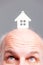 Senior balding man looking up at a model house