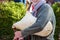 Senior bearded man is sweater and scarf playing old sheepskin bagpipe outdoors - cropped and selective focus