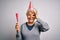 Senior beautiful grey-haired woman celebrating birthday wearing funny hat holding trumpet with happy face smiling doing ok sign