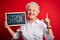 Senior beautiful woman holding blackboard with strong message over isolated red background surprised with an idea or question