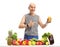 Senior behind a table with fruit and vegetables holding a glass