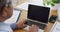 Senior biracial male doctor sitting at desk using laptop, copy space on screen