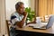 Senior biracial man doing paperwork and using laptop in dining room