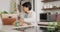 Senior biracial woman grabbing vegetables from box in kitchen alone