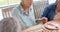 Senior biracial woman holds hands with someone at a table