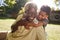 Senior black man sitting on grass, embraced by his grandson