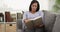 Senior black woman reading book on couch at home