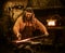 Senior blacksmith forging the molten metal on the anvil in smithy