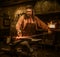 Senior blacksmith forging the molten metal on the anvil in smithy