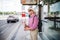 Senior blind man with white cane waiting at bus stop in city.