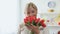 Senior blond lady sniffing tulips bouquet looking in camera, holiday present