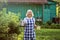 Senior blonde beautiful woman going with teapot to her guests at her farm