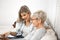 A senior blonde woman has a tablet in her hand while a young woman explains how to use the internet,iptv, social networks and