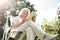 Senior blonde woman sitting in chair and using digital tablet in garden