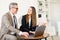 A senior businessman is engaged in a cheerful conversation with a young female