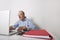 Senior businessman using laptop with book binder and cell phone on office desk