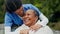 Senior care, old woman and nurse on bench in garden with blanket, smile and support in retirement. Kindness, elderly