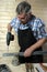 Senior carpenter drilling hole in metal plank, in his workshop