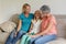 Senior caucasian grandmother on couch smiling with adult daughter and granddaughter