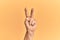 Senior caucasian hand over yellow isolated background counting number 2 showing two fingers, gesturing victory and winner symbol