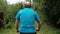 Senior caucasian male in blue t-shirt enjoying his summer vacation riding a bicycle outdoor between trees.