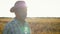 Senior caucasian man in a cowboy hat walk in a field of wheat at sunset close up