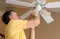 Senior caucasian man replacing bulb in ceiling fan and light