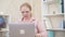 Senior Caucasian redhead woman opening laptop and typing on keyboard. Portrait of mature businesswoman in pink shirt