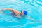 Senior caucasian woman in activity swimming in freestyle stroke. Pratice sport in the swimming pool. Outdoor under the sunlight.