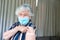 Senior caucasian woman in face mask showing plaster after vaccination