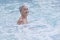 Senior caucasian woman with gray short wet hair enjoying in outdoor thermal swimming pool.