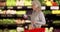 Senior Caucasian woman standing in grocery store looking at can of tuna