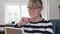 Senior Caucasian woman writing email on tablet computer in living room