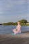 Senior Caucasian Woman During Yoga Relaxing Training On Wooden Stage Near Water Outdoor