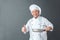 Senior chef studio standing isolated on gray holding pan looking camera cheerful thumb up