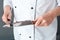 Senior chef studio standing isolated on gray sharpening knives close-up
