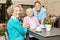 Senior citizen drinks coffee with visit and caregiver