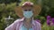 Senior citizen gardening while wearing a protective face mask due to global pandemic.